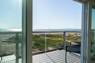 a view of the beach from the porch of a house at Luxury Beachfront Condo - Endless Views - Surf 1 in Sunset Beach