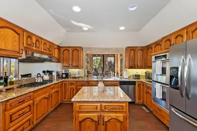 a large kitchen with wooden cabinets and stainless steel appliances at Stunning LAKE VIEW Game Room Spa Walk To Village in Lake Arrowhead