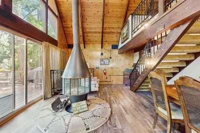 a living room with stairs and a fireplace at Retro Cabin in Lake Arrowhead