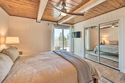 a bedroom with a bed and a large window at Ridgeline Retreat with Mountain Lake Views! in Lake Arrowhead