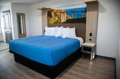 a bedroom with a blue bed with a painting on the wall at Pico Rivera Inn and Suites in Pico Rivera