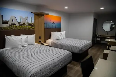 a hotel room with two beds and a table at Pico Rivera Inn and Suites in Pico Rivera