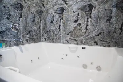 a white bath tub in a bathroom with a stone wall at Pico Rivera Inn and Suites in Pico Rivera