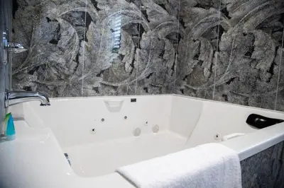 a white bath tub in a bathroom with a stone wall at Pico Rivera Inn and Suites in Pico Rivera