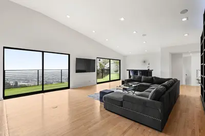 a living room with a black couch and large windows at The Hollywood Hills Crest Villa in Los Angeles