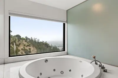 a bath tub in a bathroom with a large window at The Hollywood Hills Crest Villa in Los Angeles