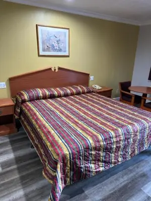 a bedroom with a bed with a colorful blanket on it at Chino Motel in Chino