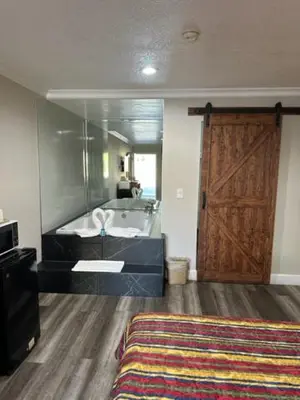 a bathroom with a bath tub and a wooden door at Chino Motel in Chino