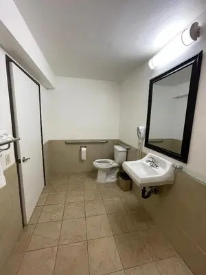 a bathroom with a toilet and a sink and a mirror at Chino Motel in Chino