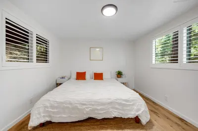 a white bedroom with a large bed with orange pillows at Red Cottage Charmer in Lake Arrowhead