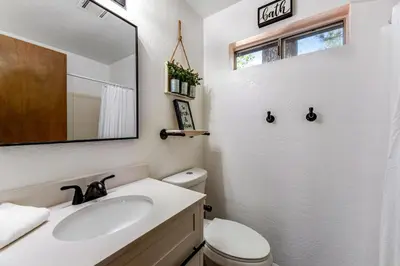 a bathroom with a sink and a mirror and a toilet at Blue Bird Beauty in Running Springs