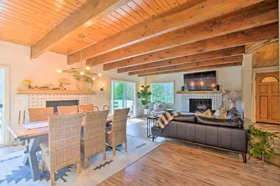 a living room with a couch and a table and a fireplace at Picturesque Cabin 2 Balconies, Walk to Lake! in Crestline