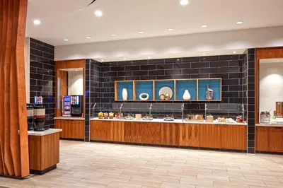 a restaurant with a counter in a room with black tiles at SpringHill Suites by Marriott Los Angeles Downey in Downey