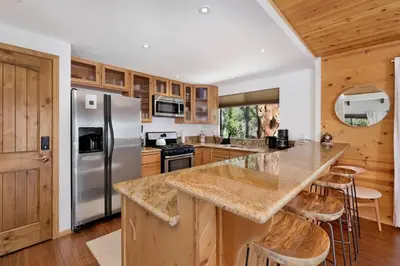 a kitchen with a stainless steel refrigerator and wooden cabinets at Chimney Peak Chalet #2048 by Big Bear Vacations in Big Bear City