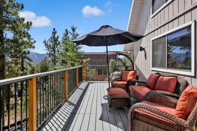 a balcony with chairs and an umbrella on a house at Chimney Peak Chalet #2048 by Big Bear Vacations in Big Bear City