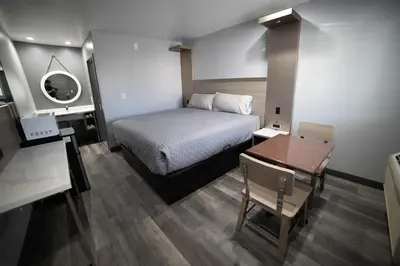 a bedroom with a bed and a table and a desk at Palms Motel in Pico Rivera