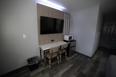 a room with a table and a television on a wall at Palms Motel in Pico Rivera
