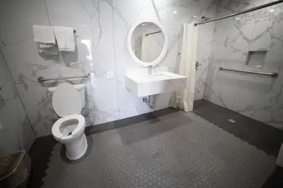 a bathroom with a toilet and a sink and a mirror at Palms Motel in Pico Rivera