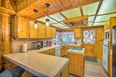 a kitchen with wooden cabinets and a counter top at Running Springs Cabin with Large Deck and View! in Running Springs
