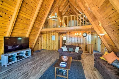 a living room with a large screen tv in a cabin at Running Springs Cabin with Large Deck and View! in Running Springs