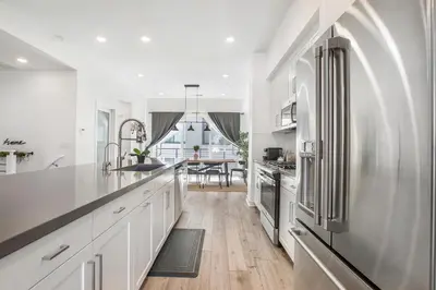 a kitchen with white cabinets and a stainless steel refrigerator at LA Harbor Home with Private Rooftop near #DTLA in San Pedro