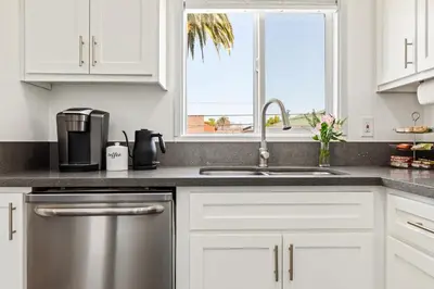 a kitchen with white cabinets and a sink and a window at Spacious Coastal Apartment in a Colorful Community - NRP22-00590 in Long Beach