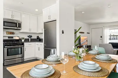 a kitchen with a table with plates and wine glasses at Spacious Coastal Apartment in a Colorful Community - NRP22-00590 in Long Beach