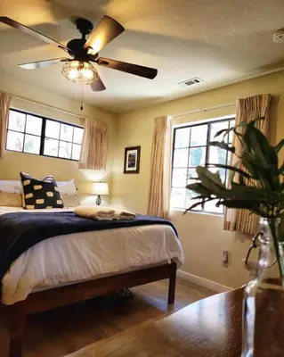 a bedroom with a bed and a ceiling fan at Treehouse Cottage in Crestline