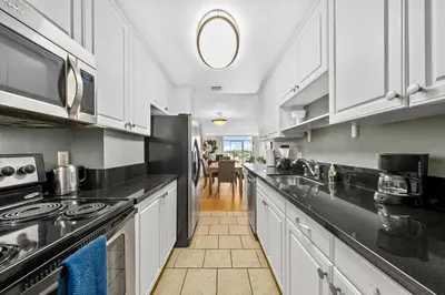 a kitchen with white cabinets and black counter tops at The tulip Marina Highrise with ocean view in Los Angeles