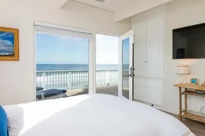 a white bedroom with a view of the ocean at Brink of Paradise in Carpinteria