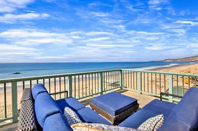 a balcony with a blue couch and the beach at Brink of Paradise in Carpinteria