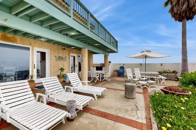a group of white chairs and an umbrella on a patio at Brink of Paradise in Carpinteria