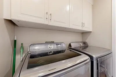 a washer and dryer in a kitchen with white cabinets at Castles Reach in Anaheim