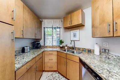 a kitchen with wooden cabinets and a sink and a window at Pacific Cove Unit 111 in Los Angeles