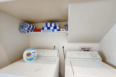 a laundry room with a washing machine and a shelf at Breakers Way Dream in Carpinteria