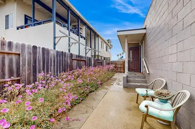 a patio with chairs and flowers next to a building at Sailaway Cabin A in Ventura