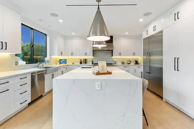 a kitchen with white cabinets and a large white island at Curson Modern in Los Angeles