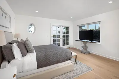 a white bedroom with a bed and a flat screen tv at Stradella Spanish in Los Angeles