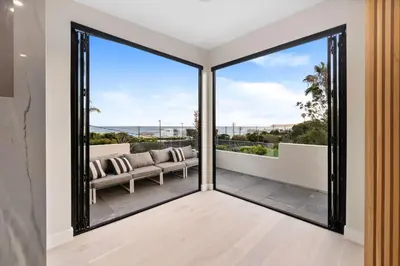 a living room with sliding glass doors with a couch on a balcony at Sea Vista in Malibu