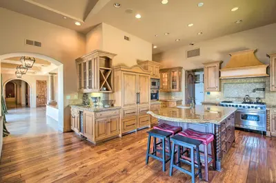 a kitchen with wooden cabinets and a large island with bar stools at Stunning Palmdale Villa Oasis on Vineyard! in Palmdale