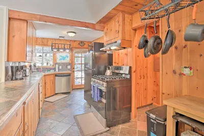 a kitchen with wooden walls and a stove top oven at Cozy Skyforest Cabin about 1 Mi to Lake Arrowhead! in Skyforest