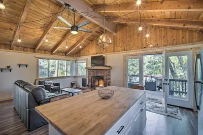 a living room with a wooden ceiling and a fireplace at Newly Renovated Lake Arrowhead Cabin with Deck! in Lake Arrowhead