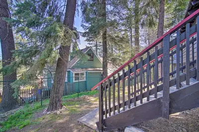 a house in the woods with a wooden fence at Newly Renovated Lake Arrowhead Cabin with Deck! in Lake Arrowhead