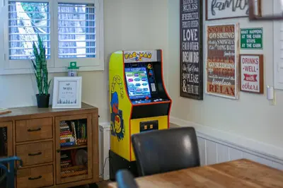 a room with a video game machine next to a table at Serene Cabin in Lake Arrowhead
