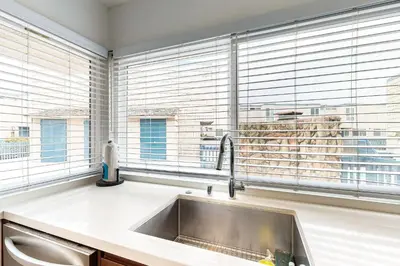 a kitchen with a sink and two windows at Hale I'a in Carpinteria