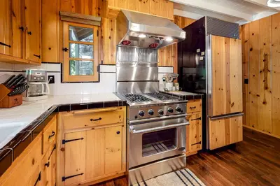 a kitchen with a stainless steel stove and wooden cabinets at Hideaway Pines in Lake Arrowhead