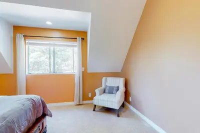 a bedroom with a bed and a chair and a window at Tree-Top Getaway in Lake Arrowhead