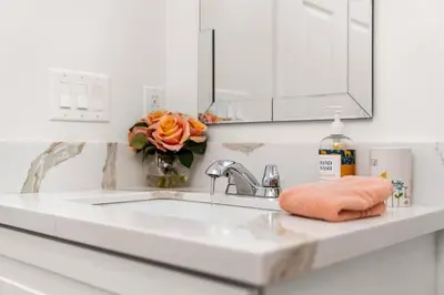 a bathroom sink with a vase of orange roses at The Avalon - 35 Percent Off March! in Los Angeles