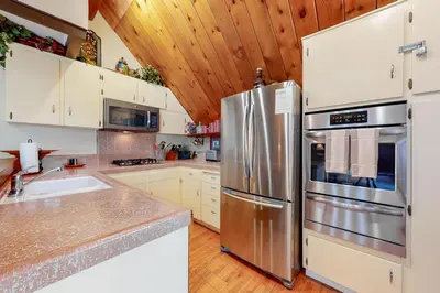 a kitchen with a stainless steel refrigerator and white cabinets at Annandale Manor in Lake Arrowhead