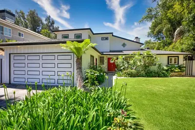 a house with a white garage and a green yard at Tullis Charm in Los Angeles